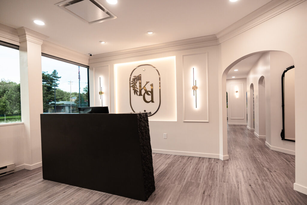 Elegant front desk at Kallos Dental in Montvale, NJ with a minimalist Trueform concrete desk, soft lighting, and calming neutral tones for a spa-like patient experience.
